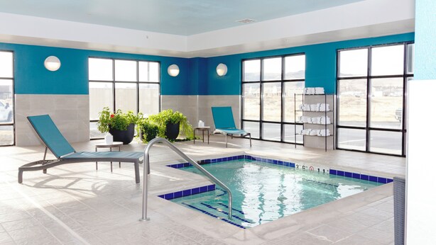 An indoor swimming pool with blue and white walls, large windows, and lounge chairs. - Hampton Inn Rawlins (Rawlins)