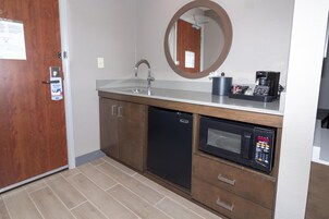 Una kitchenette compacta con un lavamanos, un microondas y una cafetera.