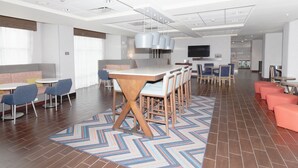 A modern hotel lobby with a central bar, seating areas, and a patterned rug. - Hampton Inn Rawlins (Rawlins)