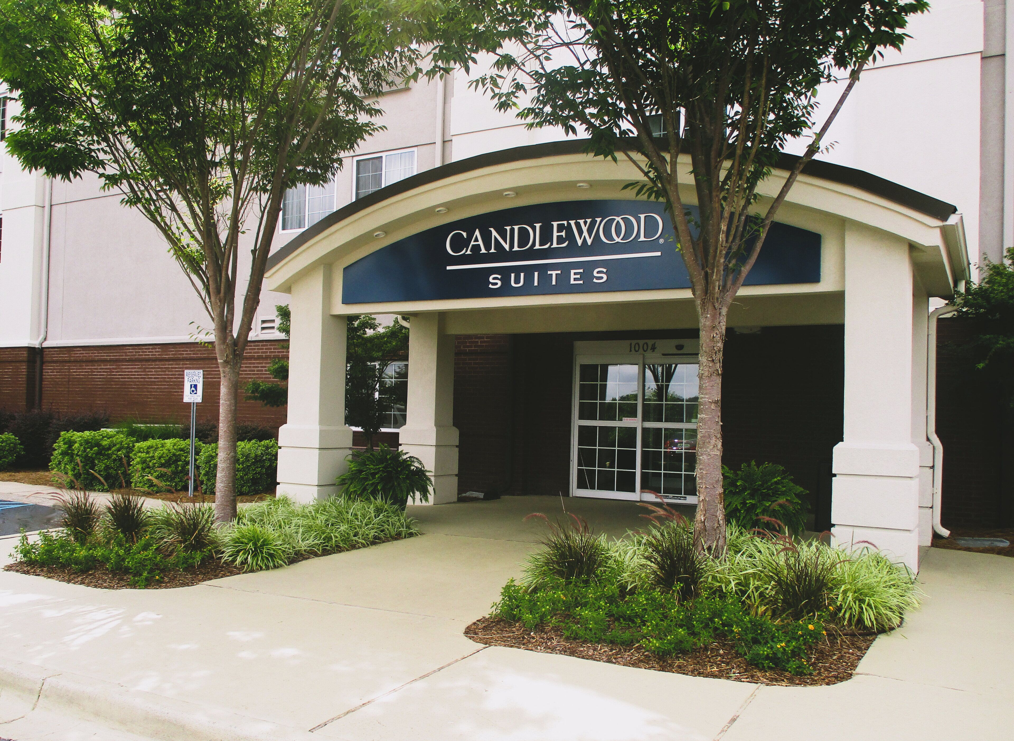 A hotel entrance with a sign reading 'CANDLEWOOD SUITES' and a number '1004' above the door.