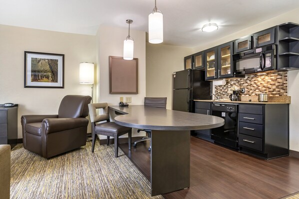 A modern kitchen with dark cabinetry, a built-in microwave, and a round dining table with chairs.