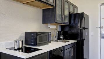A modern kitchen with a built-in microwave, a coffee maker, and a black refrigerator.