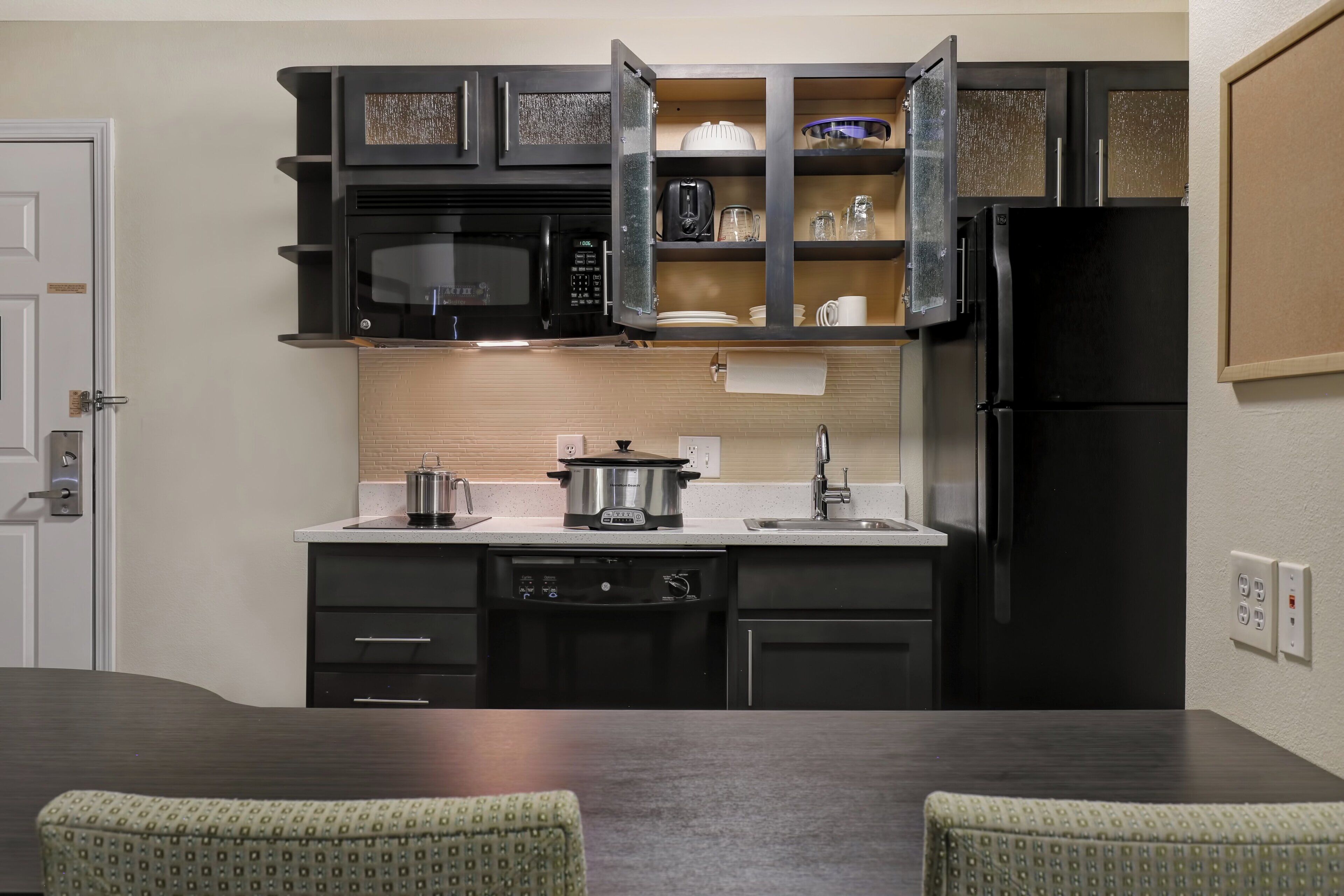 A kitchen with a microwave, toaster, and a slow cooker on the counter.