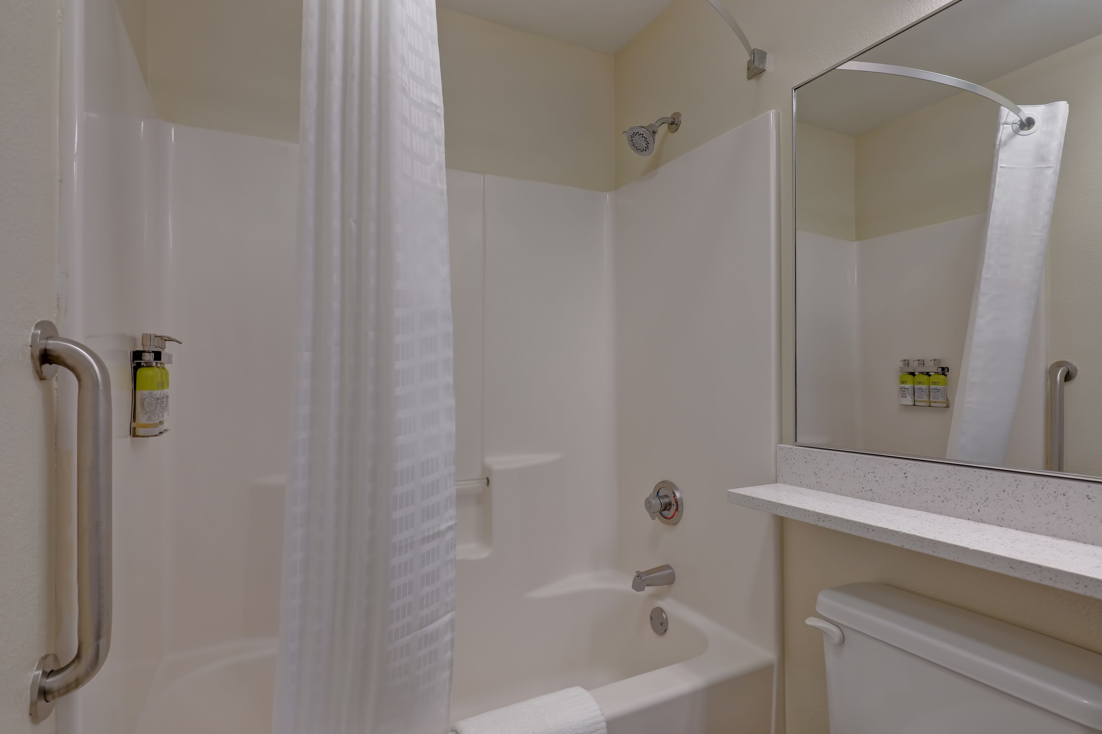 Une salle de bain équipée d’une douche, de toilettes, d’un lavabo et d’un miroir.
