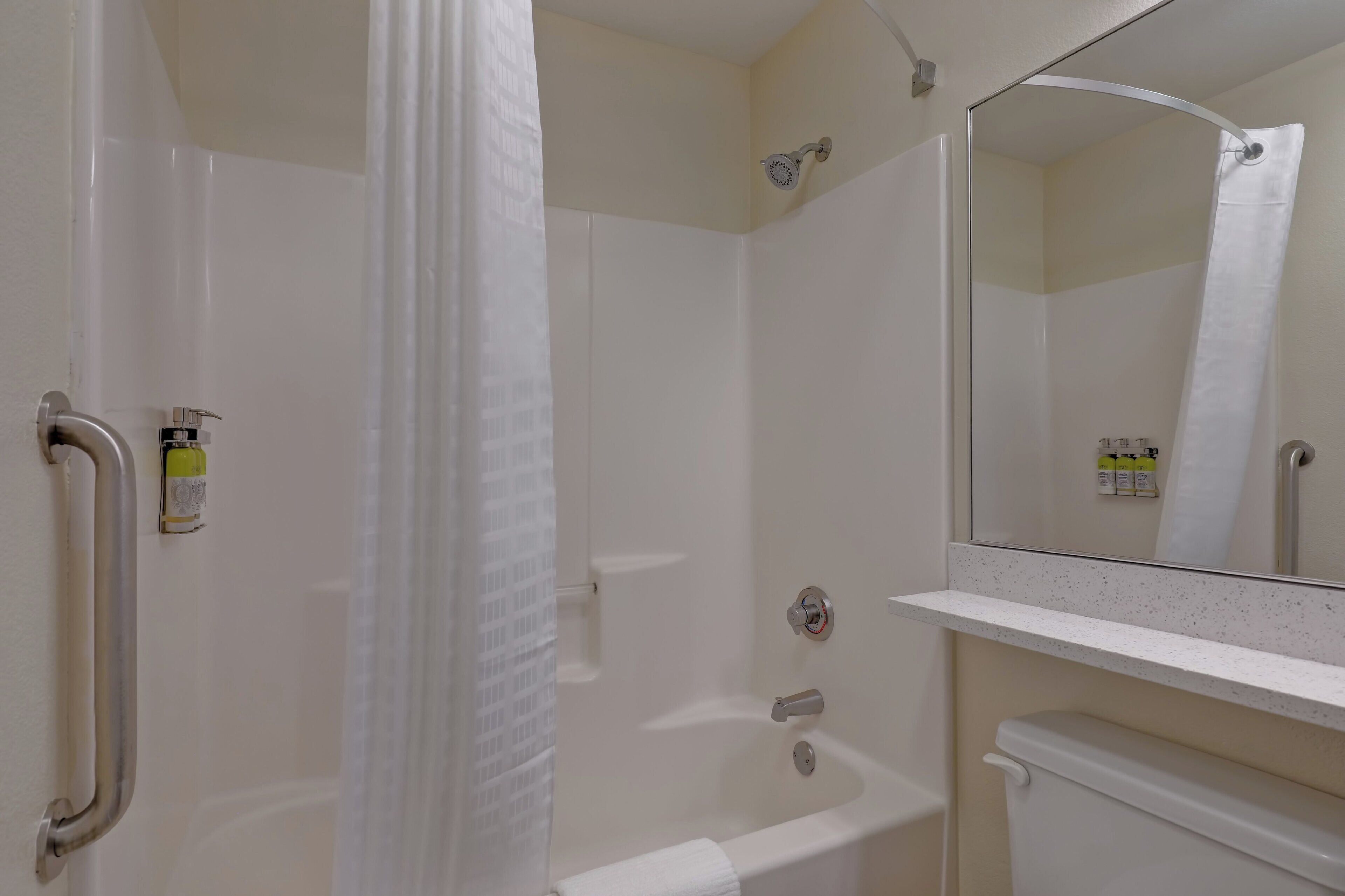 A bathroom with a shower, a toilet, a sink, and a mirror.