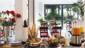 Een ontbijtbuffet met brood, fruit en een sapautomaat.