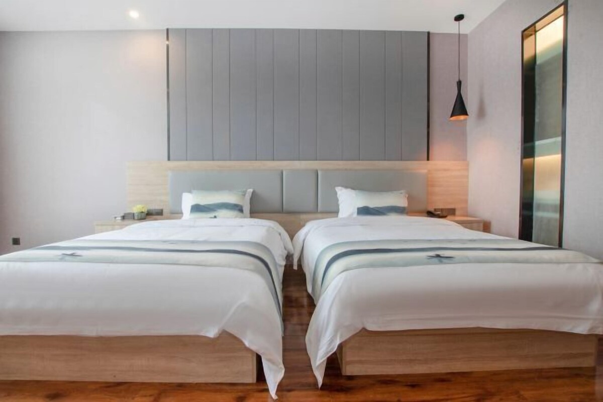 Habitación doble con cama de madera, mesitas de noche y lámpara colgante.