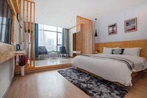 Una habitación de hotel moderna con una cama grande, un escritorio, una silla y vistas a la ciudad.