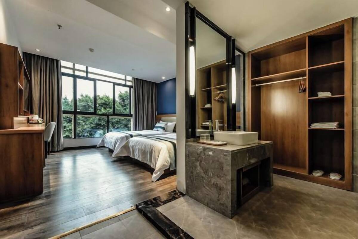 A modern bedroom with a large bed, a desk, a vanity with a mirror, and a walk-in closet.