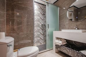 A bathroom with a toilet, shower, and vanity with a mirror. - Carol Hotel (Chongqing)