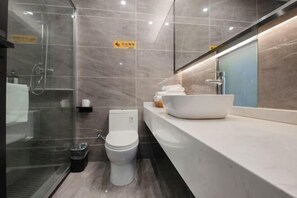 A modern bathroom with a glass-enclosed shower, a white toilet, and a white sink with a mirror above it. - Carol Hotel (Chongqing)