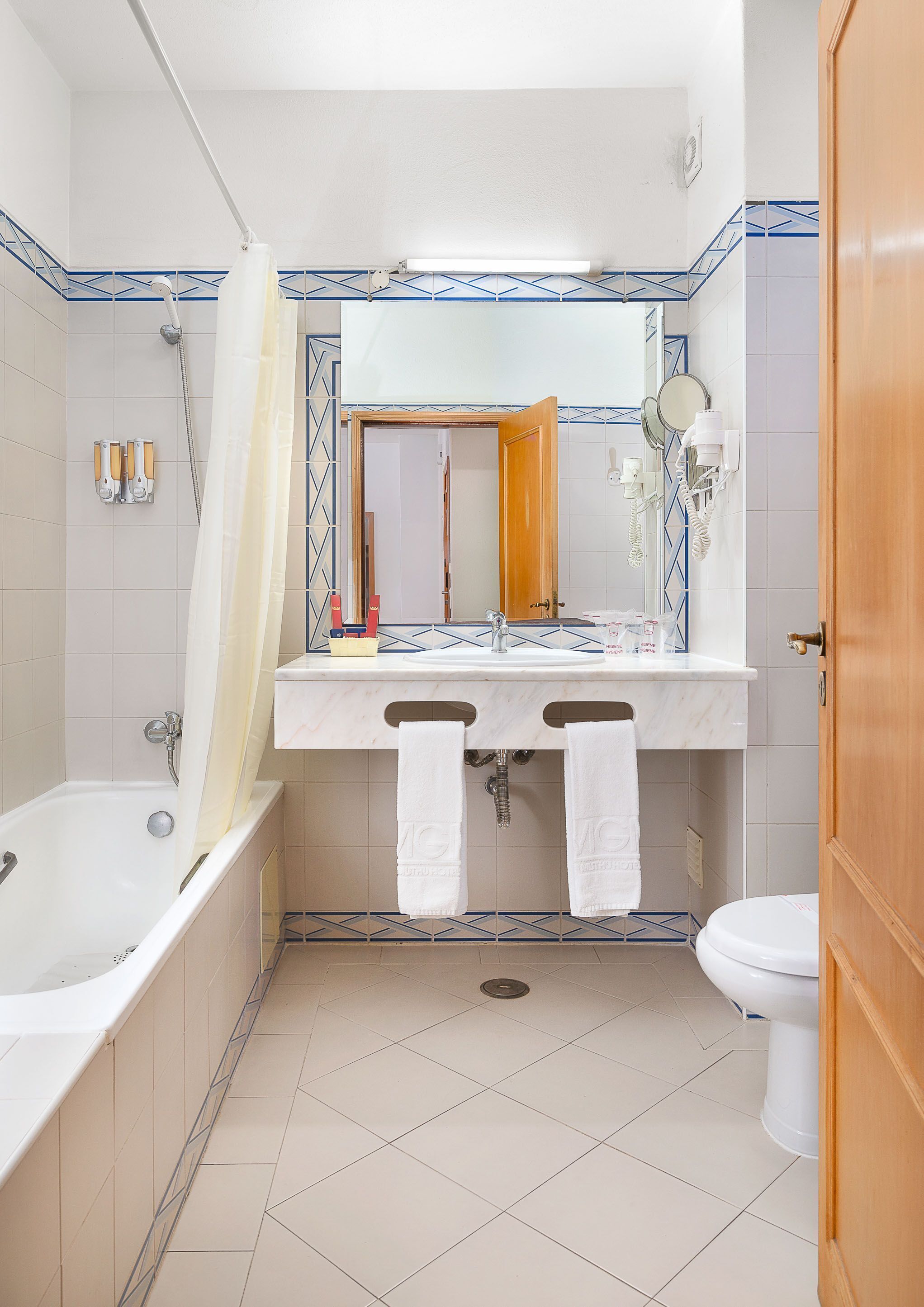 A bathroom with a bathtub, a sink with a mirror, and a toilet.
