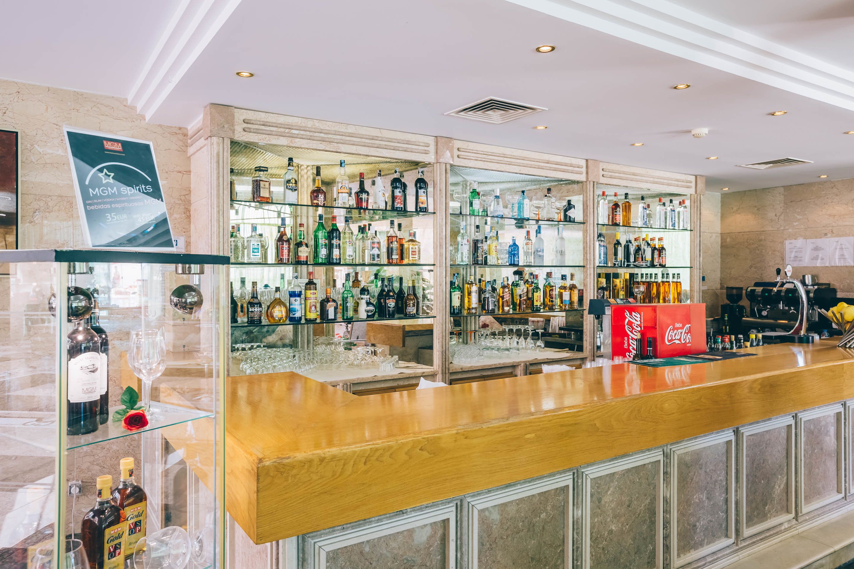 A bar area with a wooden counter and glass display cases filled with various liquor bottles.