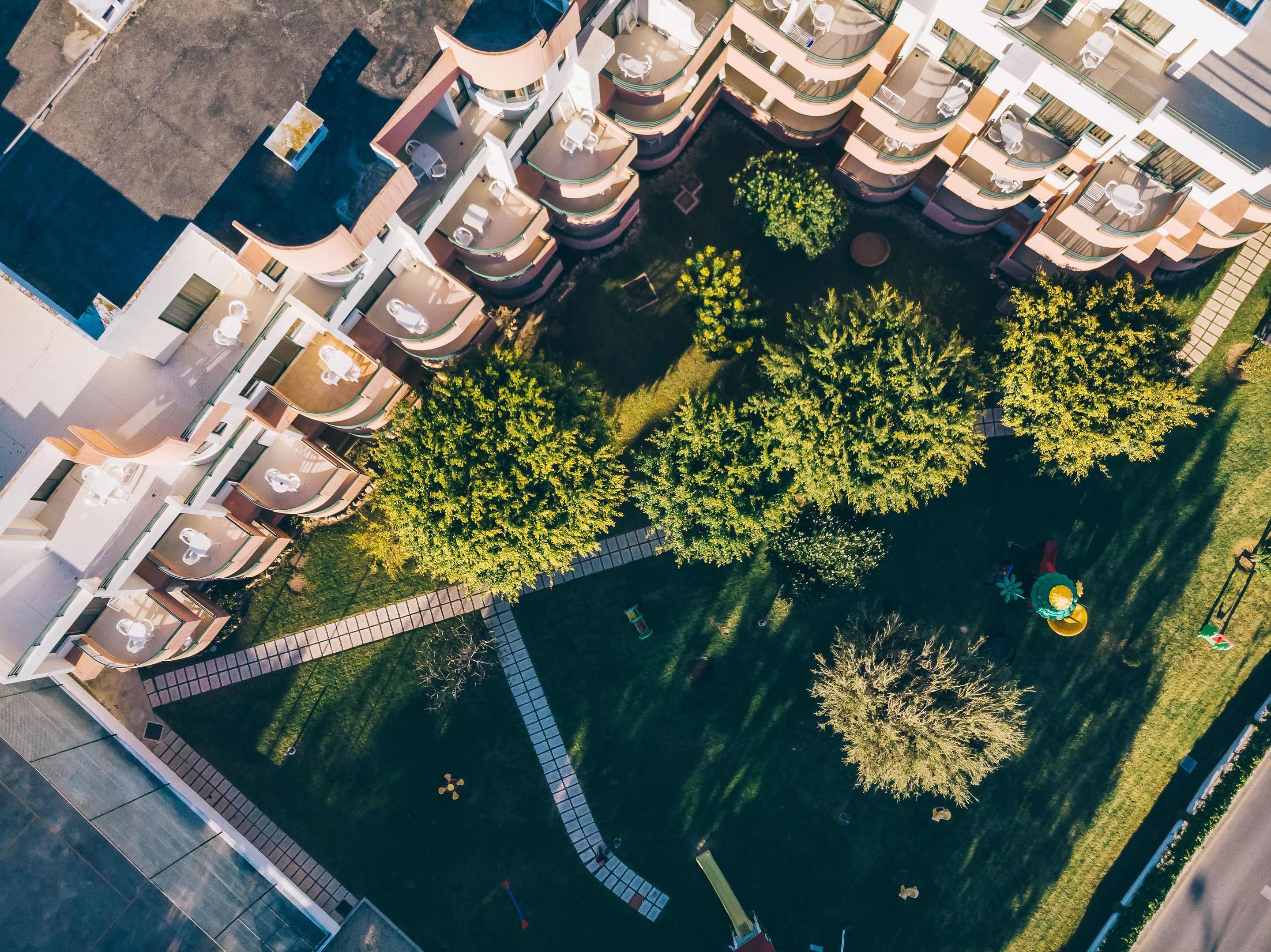 Une vue aérienne d’un hôtel doté de nombreux balcons, d’une cour intérieure avec des arbres et d’une piscine.