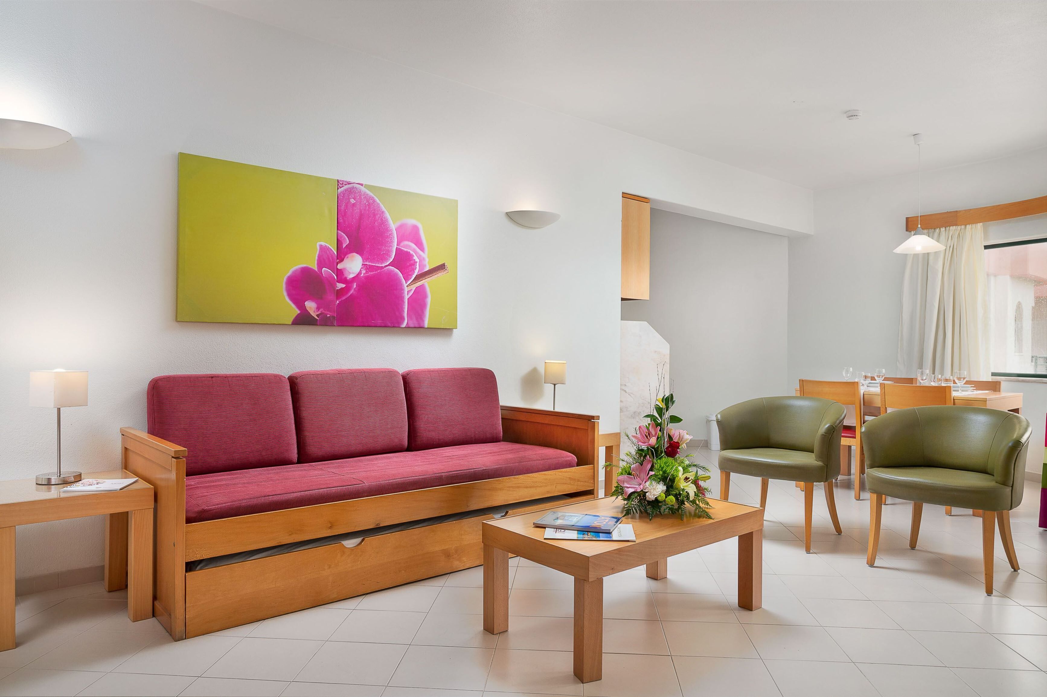 A modern living room with a red sofa, a wooden coffee table, and green chairs.