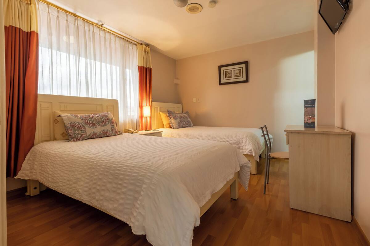 A bedroom with two beds, a desk, and a wardrobe.