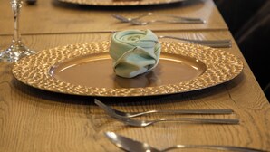 A long dining table set with gold-rimmed plates, neatly folded napkins, and cutlery. - Sandmelis (Quito)