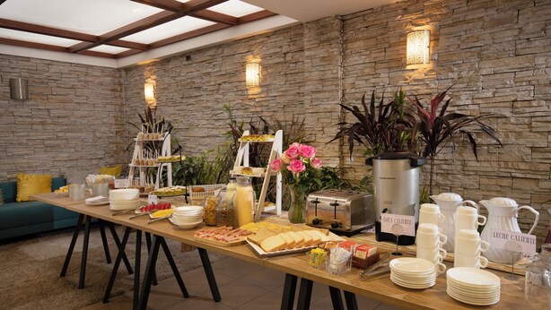 A breakfast buffet with various food items, a coffee maker, and a toaster. - Sandmelis (Quito)
