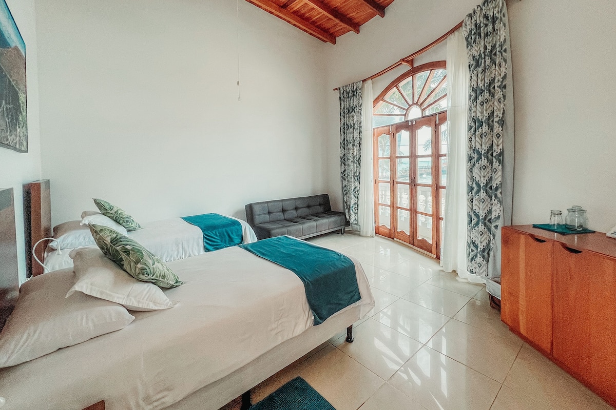 A bedroom with a bed, a sofa, a wooden cabinet, and a window with curtains.