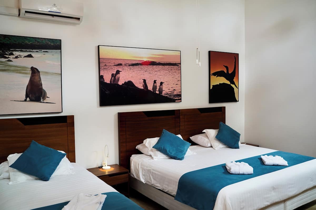 A hotel room with two beds, a nightstand, and wall art depicting wildlife.