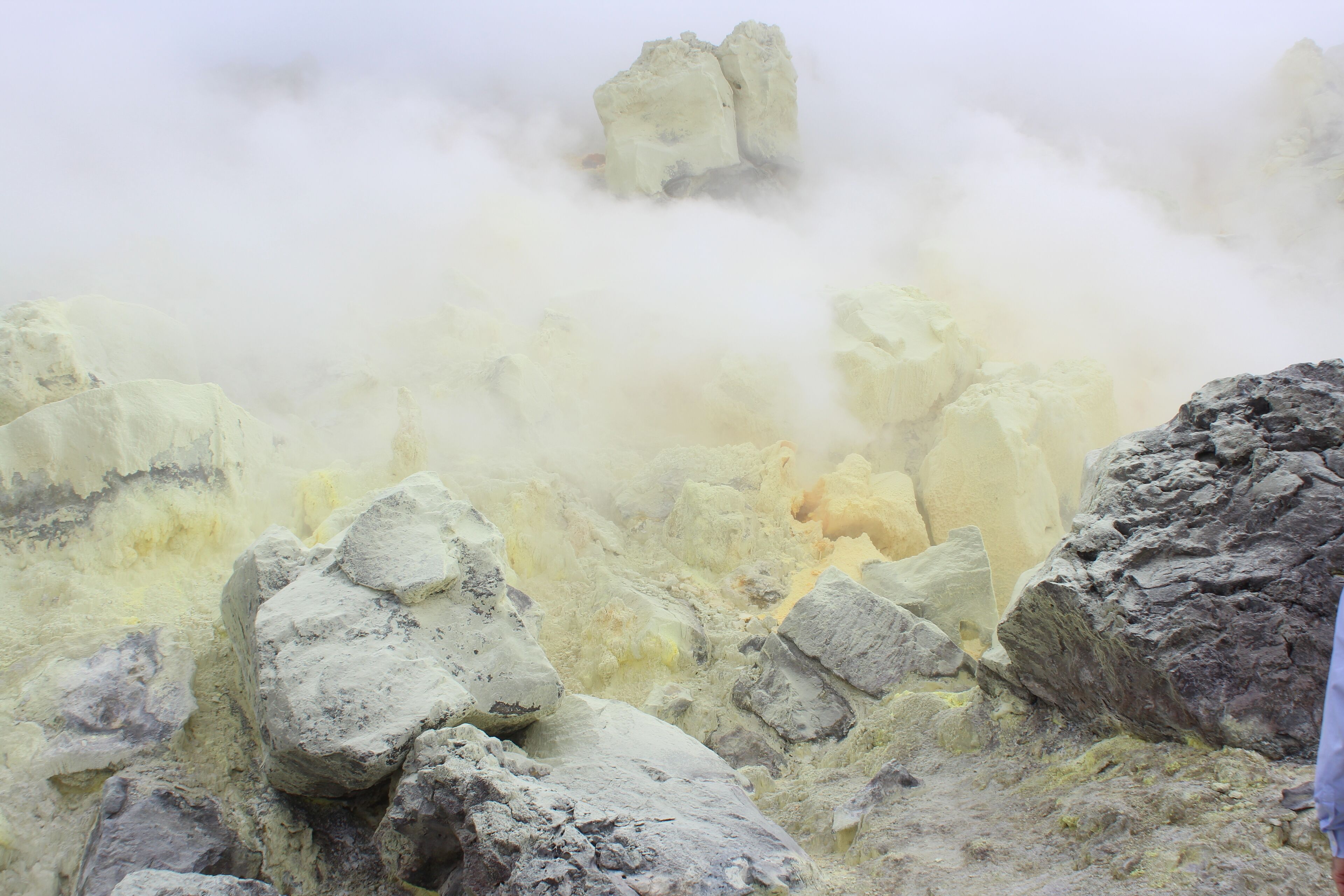 A rocky landscape with steam rising from the ground, indicating geothermal activity.