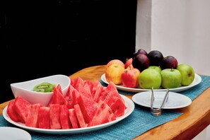 Une table avec des assiettes remplies de tranches de pastèque, de kiwis, de pommes et de prunes.