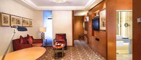 Une chambre d’hôtel équipée d’un canapé, d’un fauteuil, d’un bureau et d’une télévision.