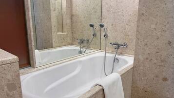 Un baño con bañera, ducha y espejo.