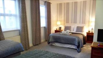 A hotel room with a bed, two bedside tables, a lamp, and a TV.