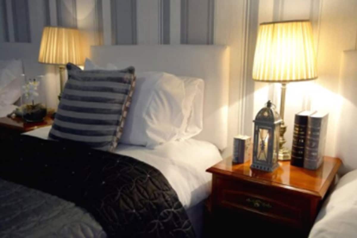 Ein ordentlich bezogenes Bett mit gestreifter Bettwäsche, ein Nachttisch mit Lampe und ein kleines Dekorationsstück.