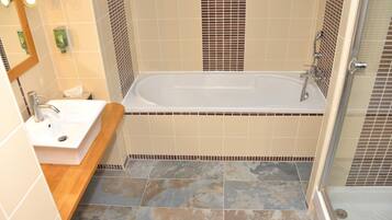 A bathroom with a bathtub, a sink, and a mirror.