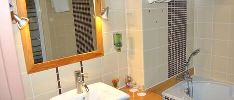 A bathroom with a sink, mirror, and bathtub.