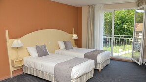 A hotel room with two beds, a balcony with a railing, and a view of greenery outside. - Domaine Golf Albon (Albon)