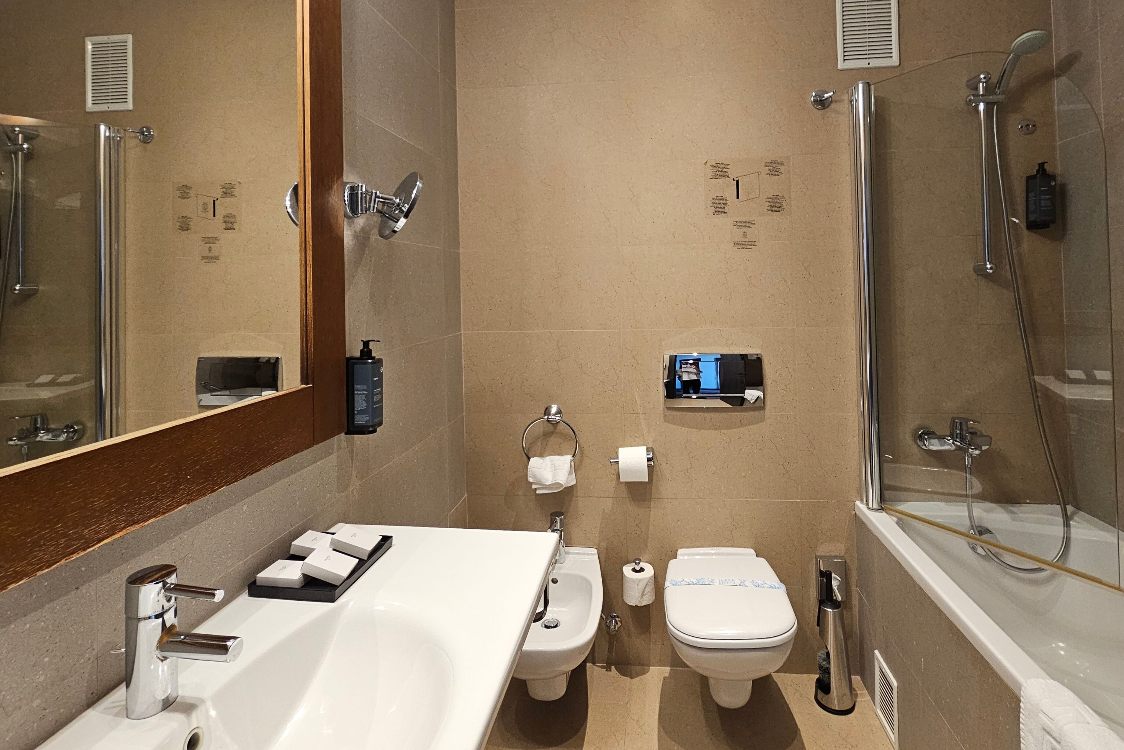 Une salle de bain moderne dotée d’un grand lavabo, de deux toilettes, d’un bidet et d’une douche séparée par une paroi en verre.