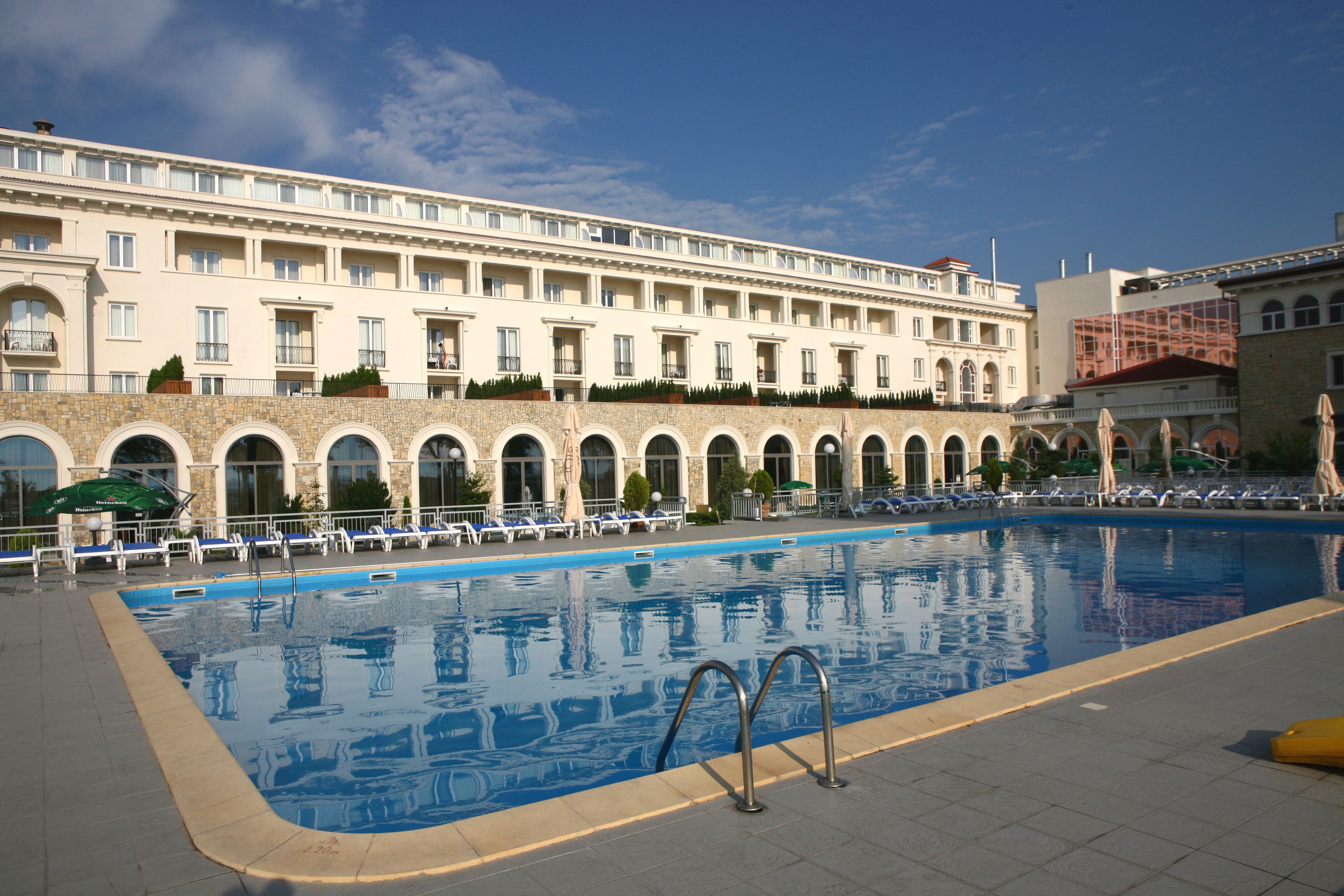 A large outdoor swimming pool with a stone facade building in the background.