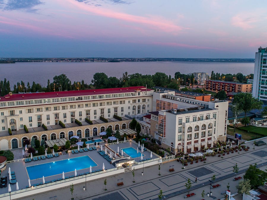 Un hotel con una grande piscina, area salotto esterna e vista sull'acqua.