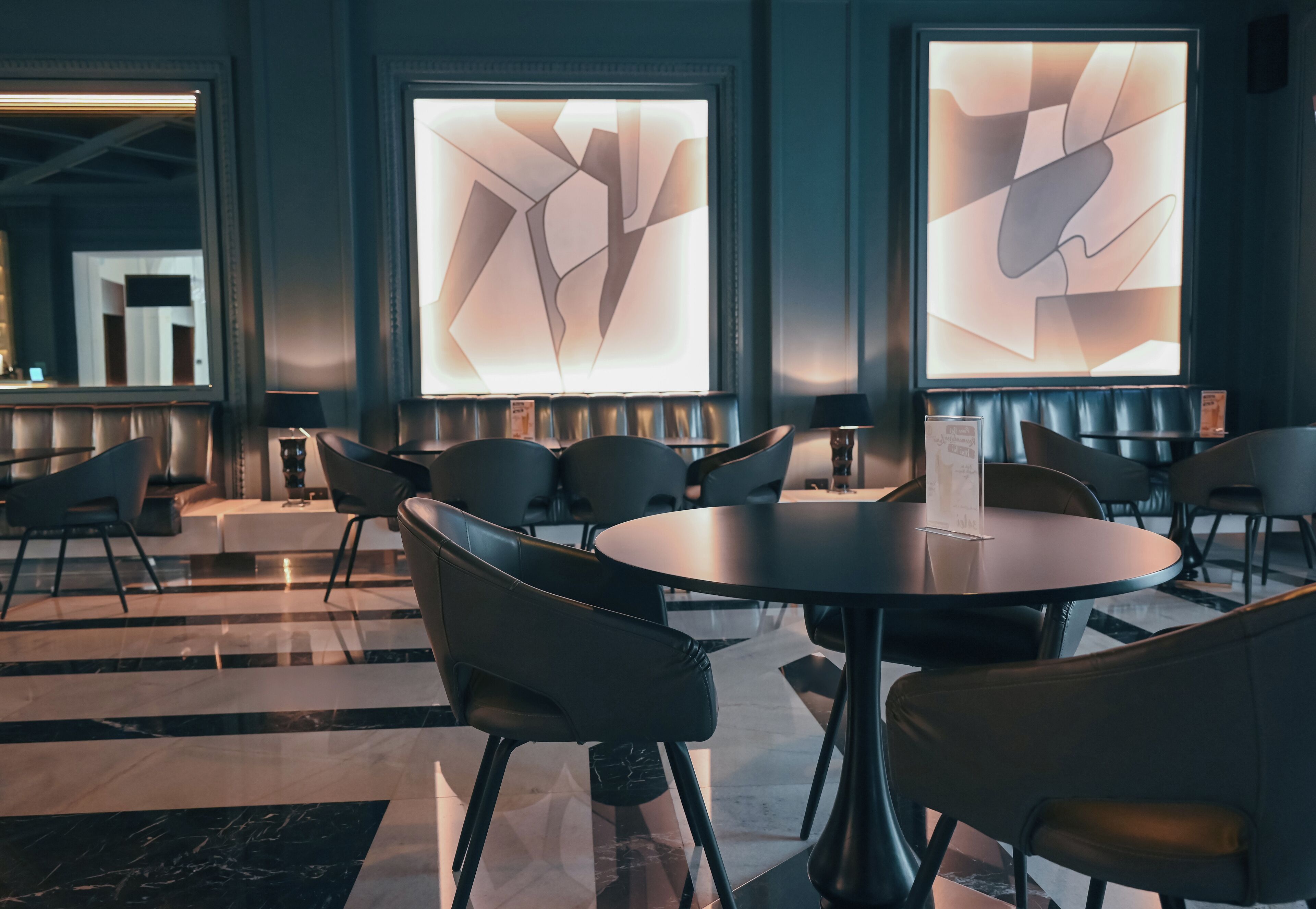 A modern hotel lobby with leather seating, abstract wall art, and a reception area.