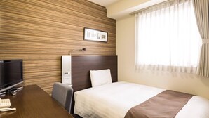 A hotel room with a wooden wall panel, a bed with a white and brown bedspread, a desk with a television and telephone, and a window with curtains. - Comfort Hotel Kumamoto Shinshigai (Kumamoto)