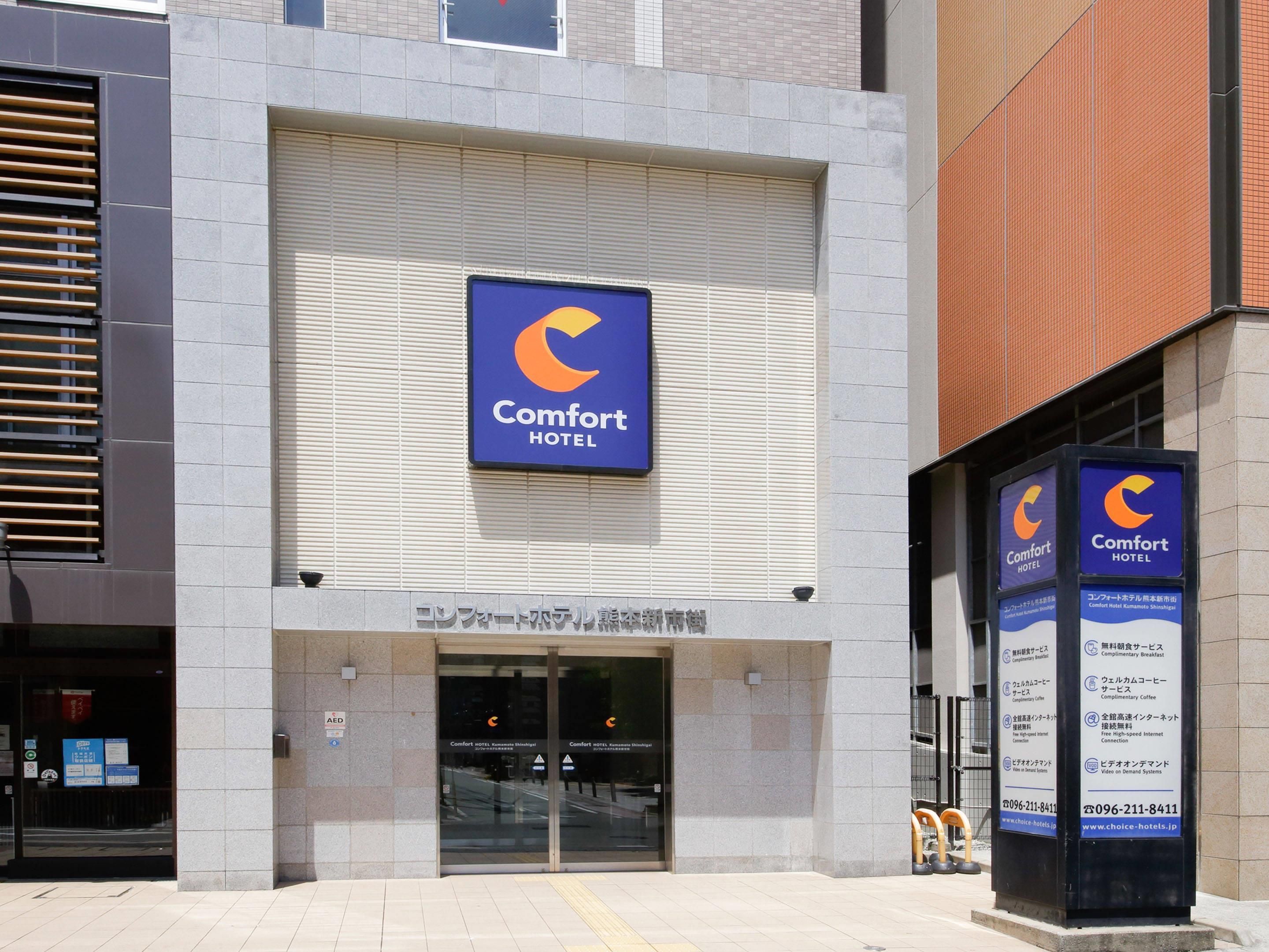 A Comfort Hotel entrance with a large sign, automatic sliding doors, and a clear view of the interior.