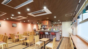 Un restaurant doté d’un plancher en bois, de nombreuses tables et chaises, d’un bar et d’un éclairage au plafond.