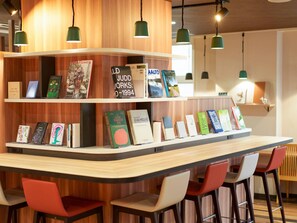 Ein stilvoller Barbereich mit Holzböden, die Bücher ausstellen, einer gebogenen Theke und roten und weißen Barhocker.