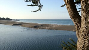 A coastal landscape with a sandy beach and calm sea. - Surf Inn (Gualala)
