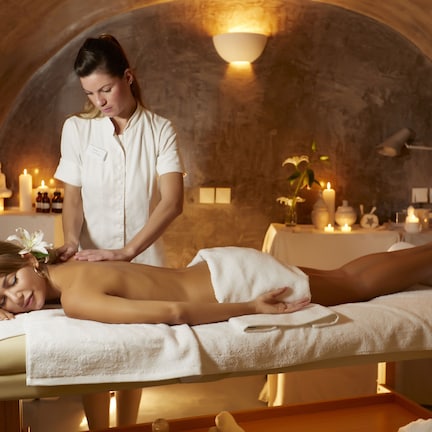 A spa treatment room with a massage table, candles, and a wall-mounted light fixture.