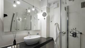 A modern bathroom with a large mirror, a round sink, and a glass shower enclosure.