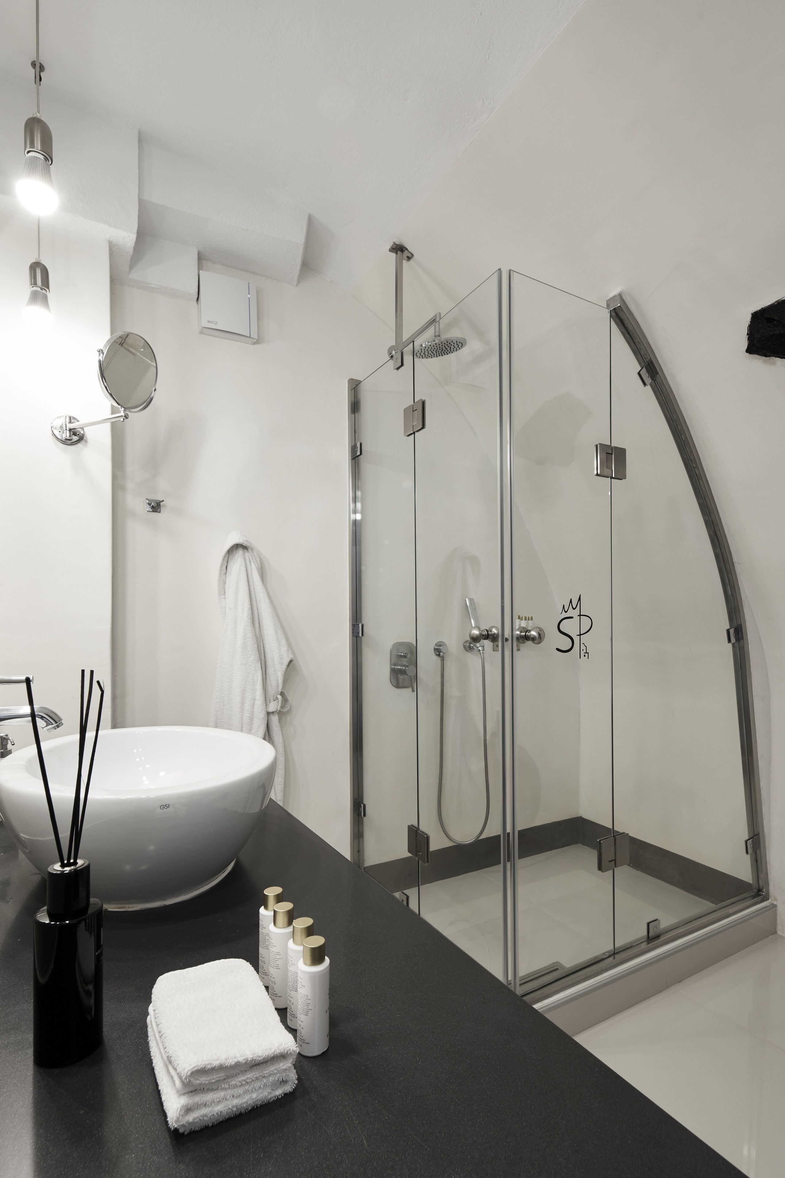 A modern bathroom with a glass-enclosed shower, a white sink, and a black countertop.