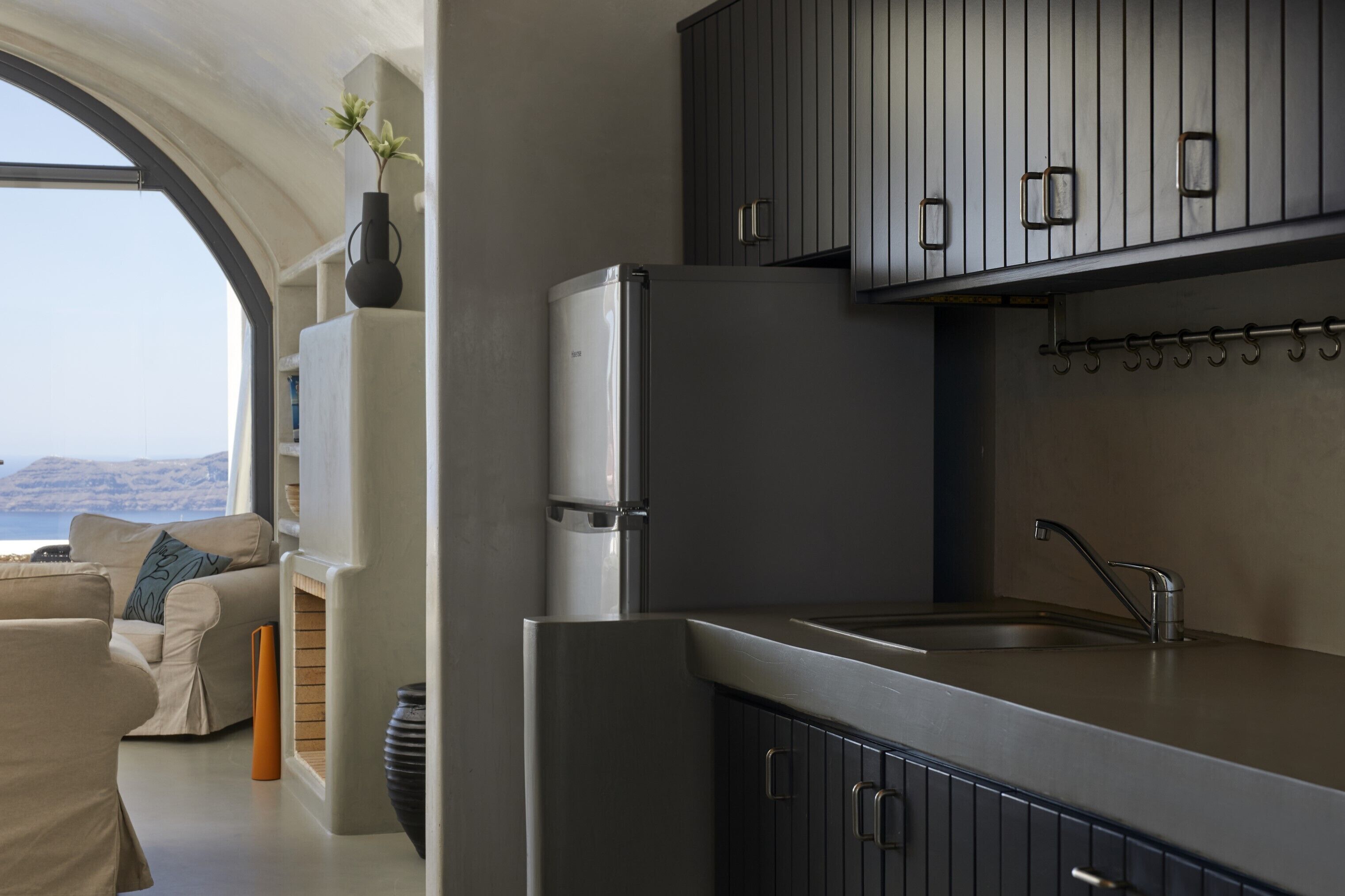 Una cocina moderna con horno empotrado, pileta de acero inoxidable y vista al mar a través de una ventana arqueada.