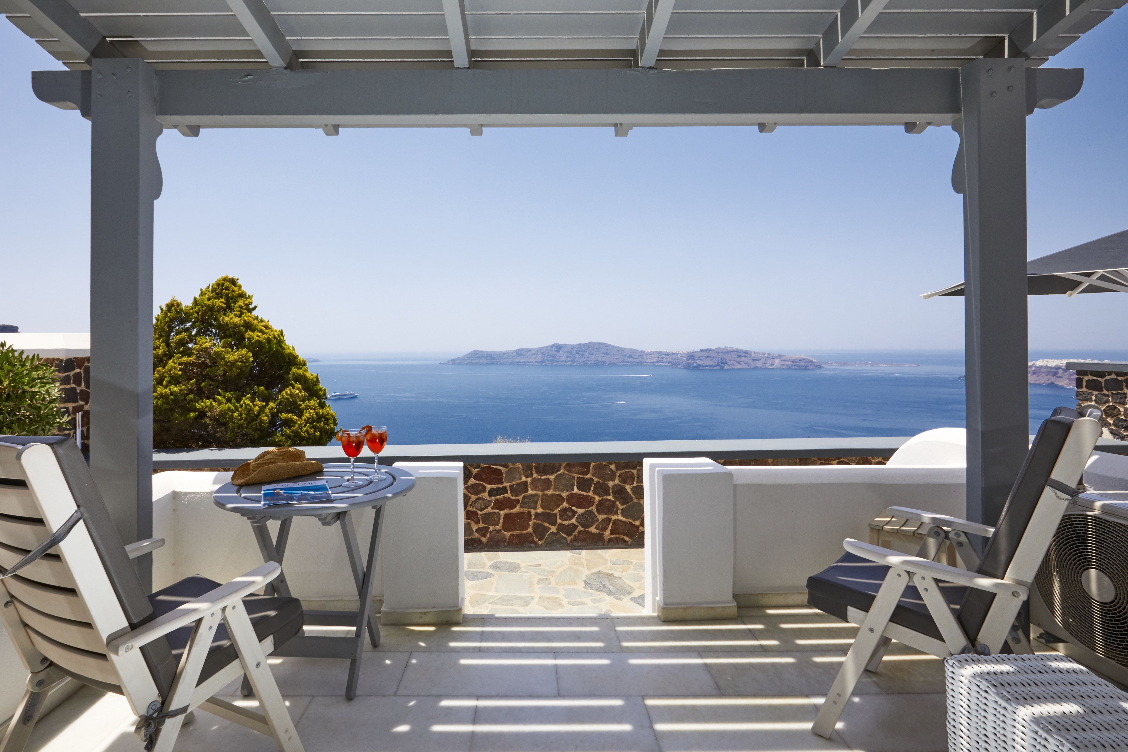 Un espacio de estar al aire libre techado con pared de piedra y vistas al mar.