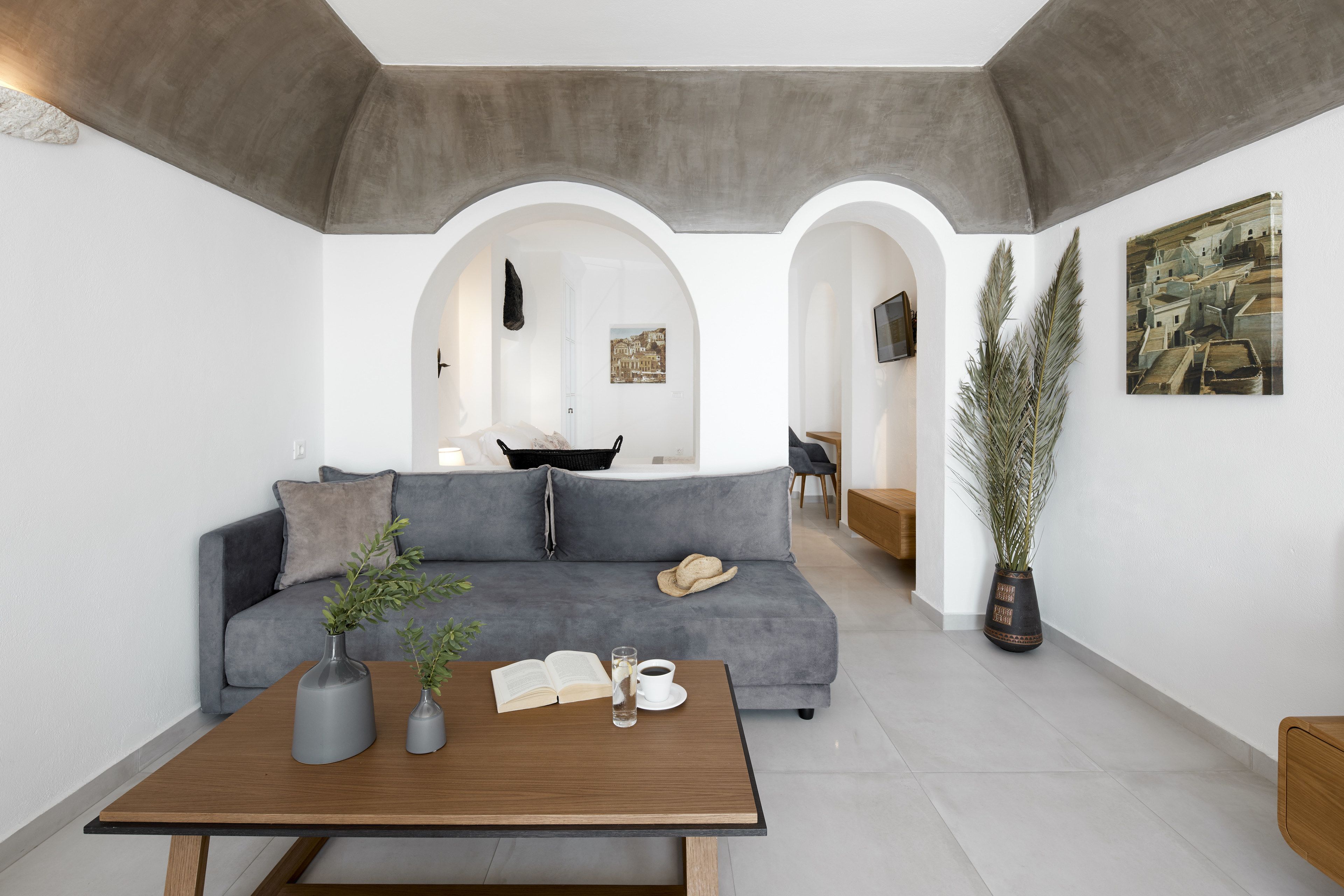 Una sala moderna con un sofá gris, una mesa de centro de madera y una planta en maceta.