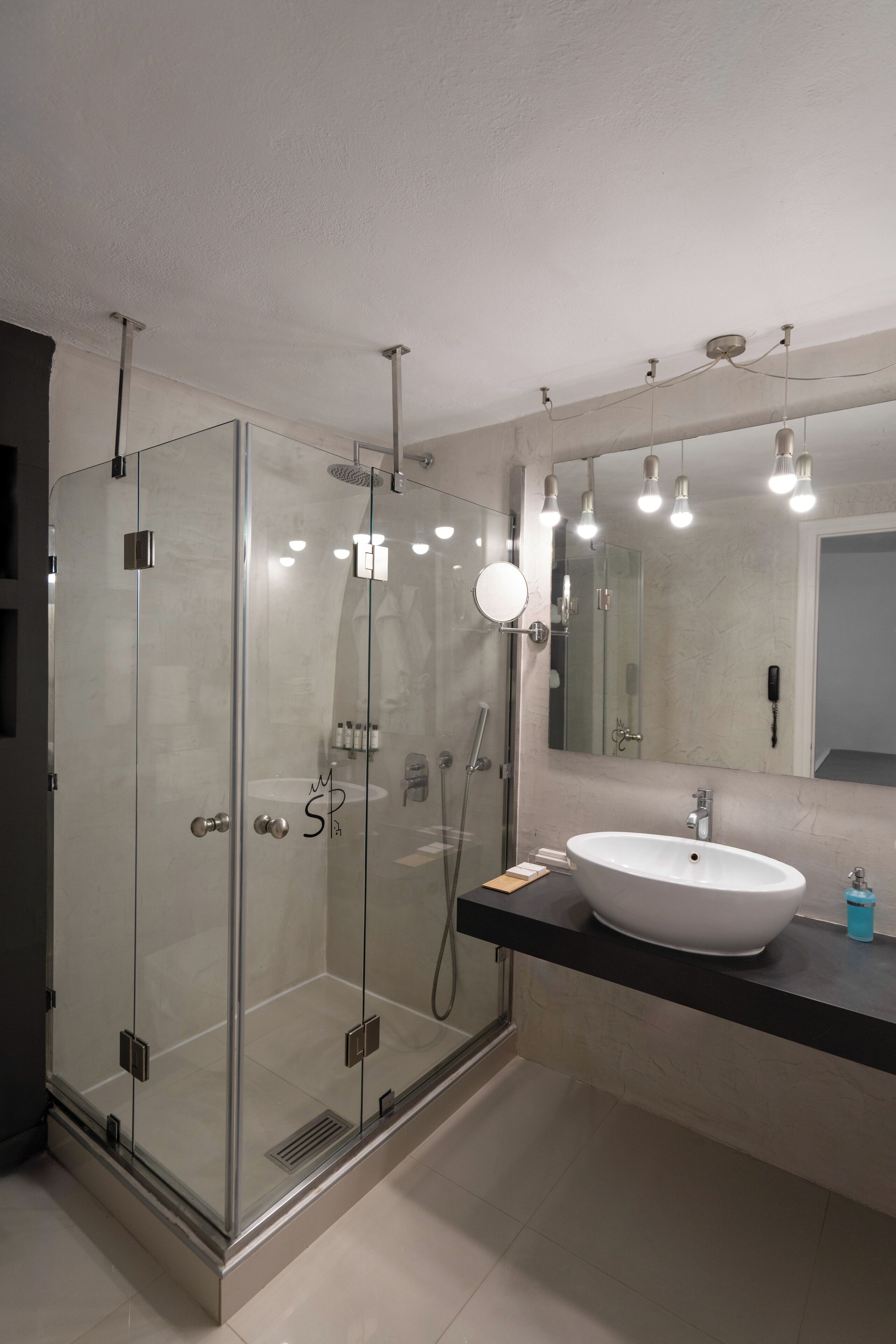 Un baño moderno con ducha de vidrio, lavamanos blanco y espejo grande.