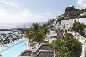 A resort with a swimming pool, white buildings, and a view of the sea. - Marina Bayview - Adults Only (Mogan)
